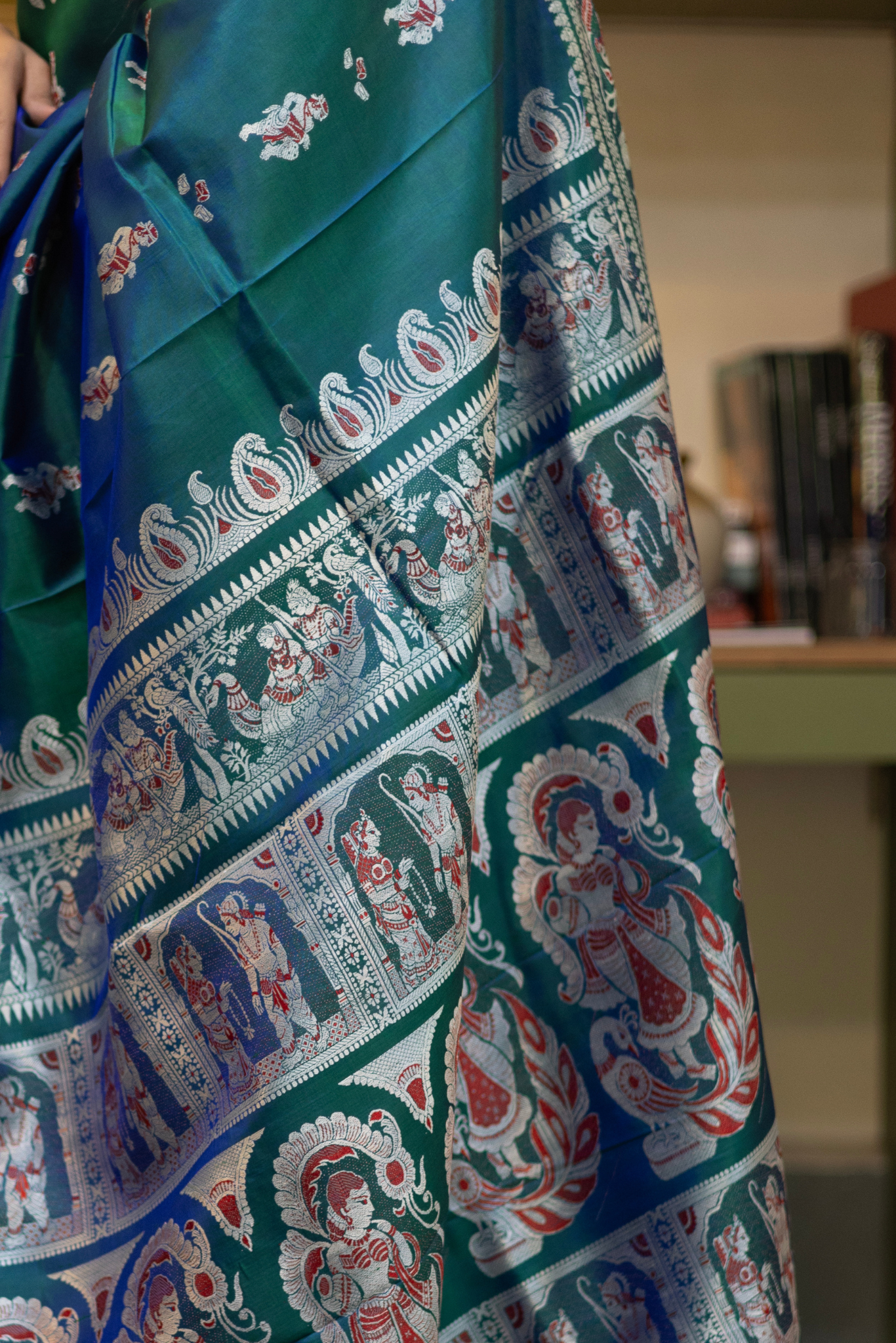 Woman in a Peacock blue and silver resham work saree standing indoors with a desk and lamp in the background.
Woman wearing a Peacock blue saree with a pattern in a elegant setting. 

Baluchari – Pure Silk Meenakari Saree

1. “Pure silk Baluchari Meenakari saree with meenakari motif weave and Silver resham detailing for a regal look.”

2. “Silk Mark pure silk meenakari saree featuring intricate gold resham work motifs and rich texture.” 