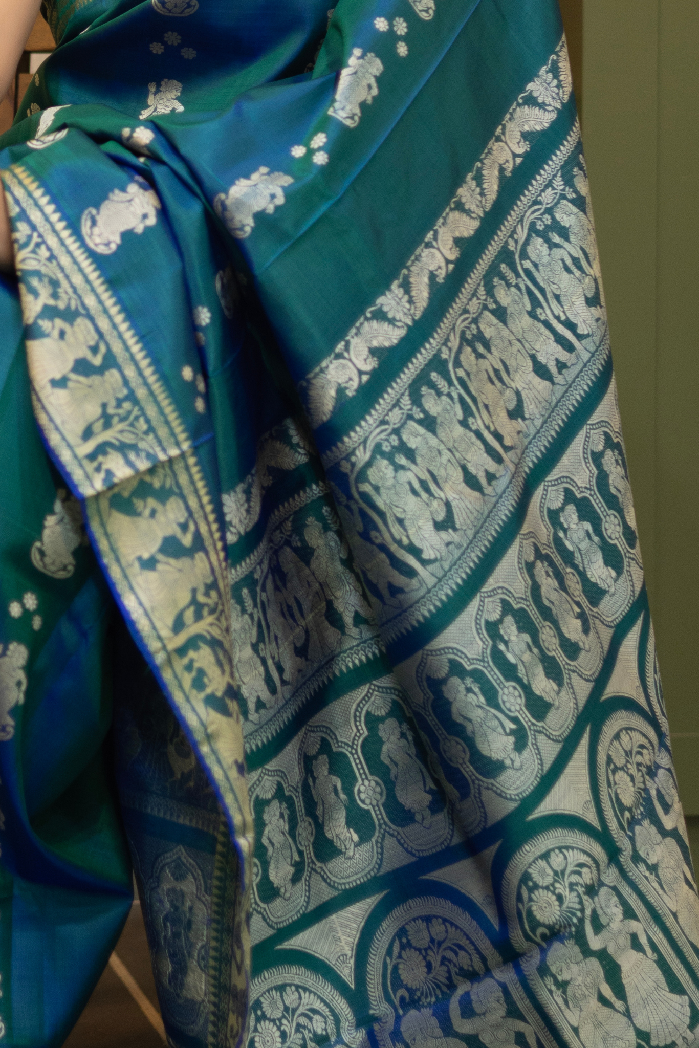 Woman wearing a traditional baluchari saree in a room with a desk and lamp. Woman in a Peacock blue and silver resham work saree standing indoors with a desk and lamp in the background.

Baluchari – Pure Silk Baluchari Saree

1. “Pure silk Baluchari saree with meenakari motif weave and Silver resham detailing for a regal look.”

2. “Silk Mark pure silk meenakari saree featuring intricate gold resham work motifs and rich texture. 